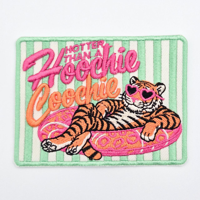Hotter Than a Hoochie Coochie Puff Embroidered Hat Patch – 4" x 3", embroidered patch featuring a relaxed tiger wearing pink heart-shaped sunglasses, lounging on a pink pool float with green and white striped background.