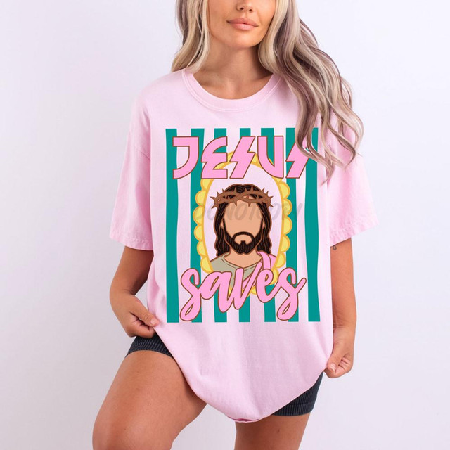 Jesus Saves DTF Heat Transfer, pink T-shirt with graphic of Jesus Christ wearing a crown of thorns and the text 'Jesus Saves' in bold, colorful letters.