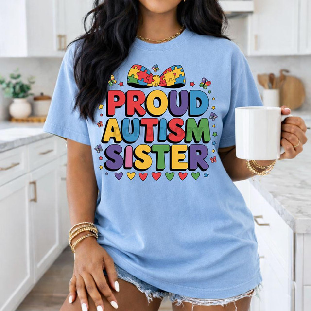 Proud Autism Sister DTF Heat Transfer, colorful design with puzzle pieces, rainbow colors, hearts, and butterflies on a blue T-shirt