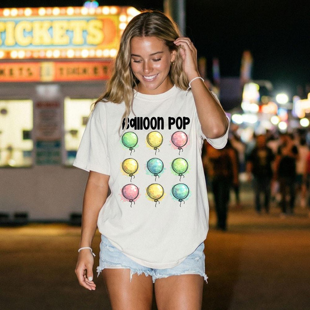 Ballon Pop DTF Heat Transfer, colorful balloon design on a woman's white T-shirt in a fun, vibrant setting.