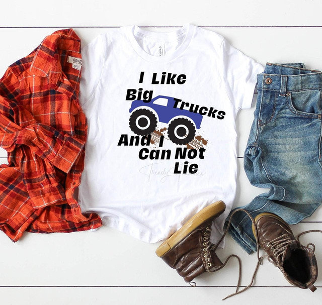 I Like Big Trucks Sublimation Transfer, white T-shirt with a graphic of a blue truck, large black wheels, and mud splashes, featuring the humorous phrase 'I Like Big Trucks And I Can Not Lie'.