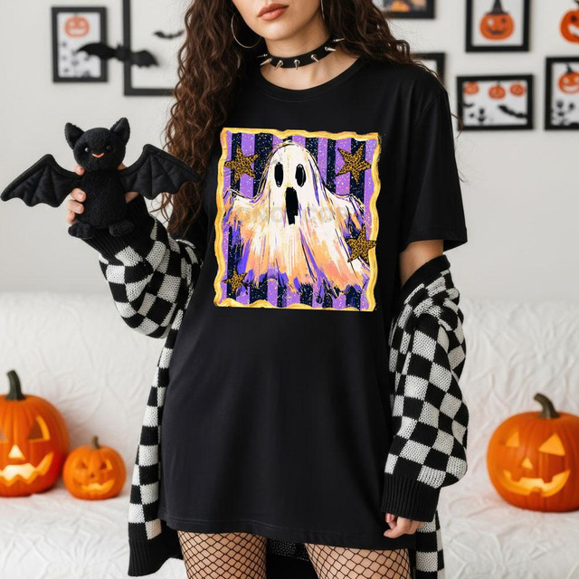Vintage Ghost DTF Heat Transfer, Halloween-themed ghost design with stars on a black t-shirt worn by a woman holding a bat plush toy.