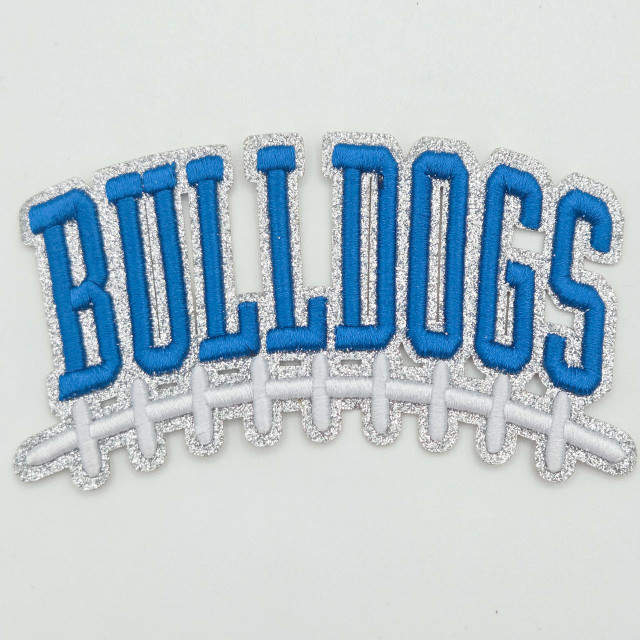 Bulldogs Blue Football Puff Embroidered Glitter Hat Patch, embroidery patch featuring the word Bulldogs in blue thread with glitter border and a football lacing design at the bottom.