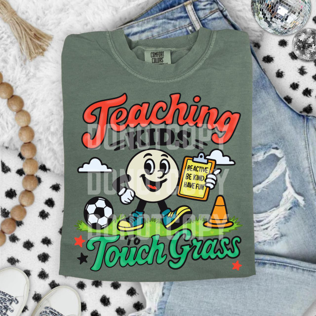 Teaching Kids To Touch Grass DTF Heat Transfer, colorful kiddie t-shirt design with a smiling cartoon ball character, soccer ball, traffic cone, and motivational words.