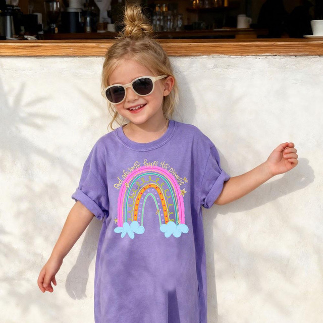 God Always Keeps His Promises DTF Heat Transfer, product image showing a young girl wearing a purple T-shirt with colorful rainbow and cloud design, and inspirational quote.