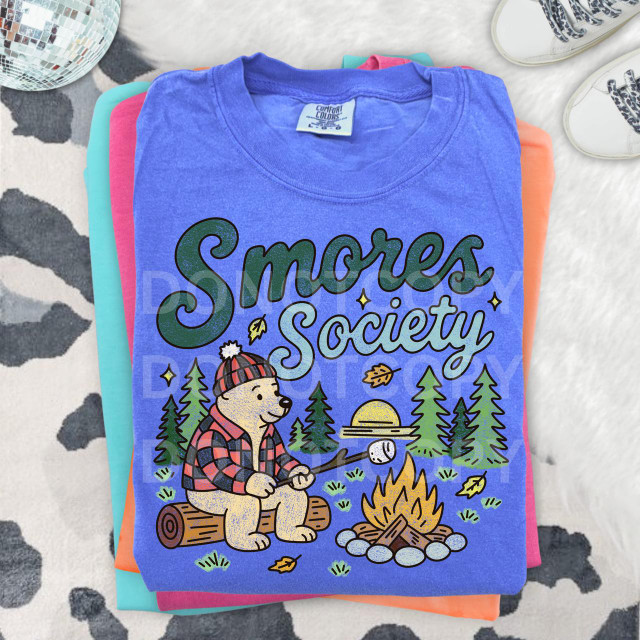 Smores Society DTF Heat Transfer, colorful design with a bear camping by a campfire, trees, and a sunset, printed on a blue T-shirt.