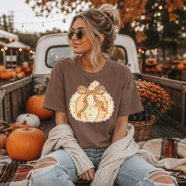 Preppy Floral Fall Pumpkin DTF Heat Transfer, woman sitting in harvest decor with pumpkins and autumn foliage.