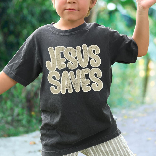 Jesus Saves TAN DTF Heat Transfer, colorful heat transfer decal on child's black t-shirt in outdoor setting