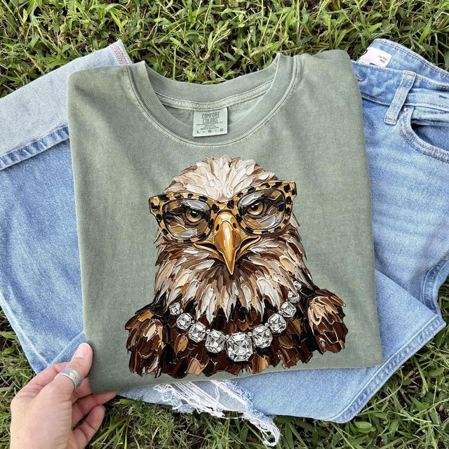 Glam Eagle DTF Heat Transfer, a graphic of an eagle wearing glasses and a bejeweled necklace on a green T-shirt.