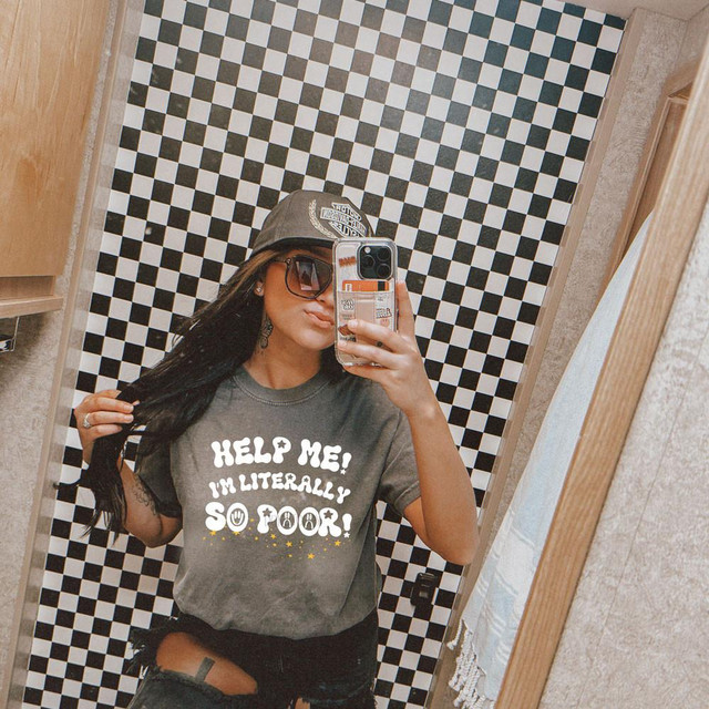 Help Me I'm Literally So Poor DTF Heat Transfer, a woman wearing a gray t-shirt with this phrase printed on it, taking a mirror selfie.