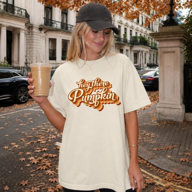 Hey There Pumpkin DTF Transfer, woman wearing a cream t-shirt with the retro fall script design in an outdoor autumn setting.