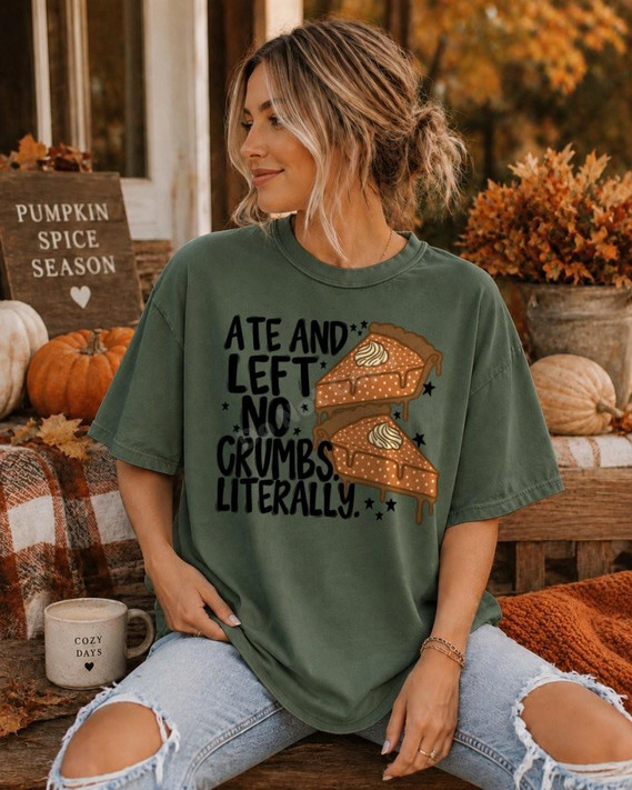 Ate and Left No Crumbs Literally DTF Transfer | Funny Pumpkin Pie Fall Design T-shirt, featuring a woman wearing an oversized green shirt with a pumpkin pie graphic and humorous text, surrounded by fall decorations.