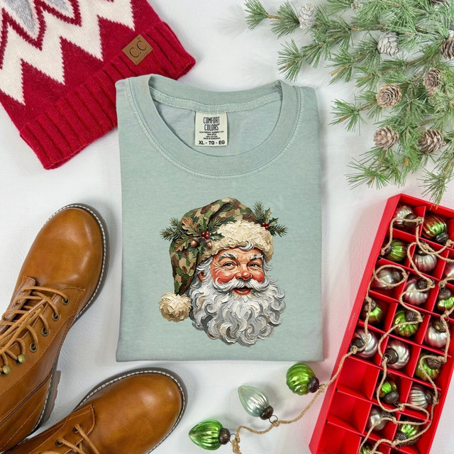 Camo Santa DTF transfer featuring a detailed Santa face wearing a camouflage hat with holly and pine accents on a sage green shirt