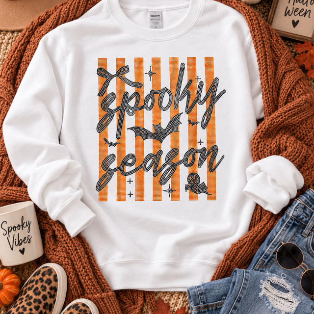 Spooky Season orange and black spangle heat transfer with bats and Halloween details shown on white sweatshirt