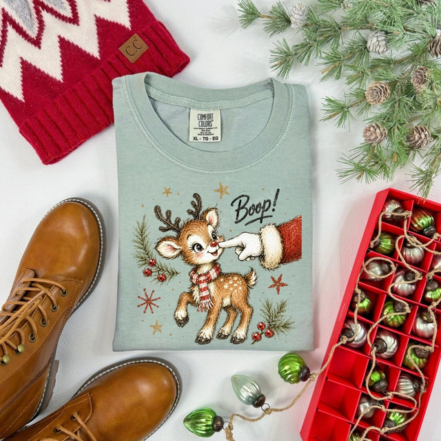 Boop reindeer DTF transfer featuring a hand-illustrated baby deer in a scarf with a mitten hand tapping its nose, surrounded by pine and snowflakes