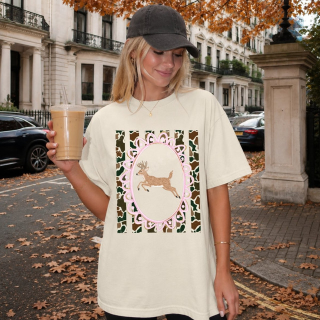 Leaping deer DTF transfer in a pink scalloped frame with green and brown camouflage stripe background