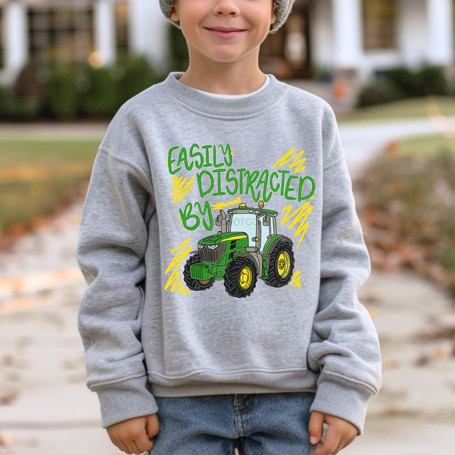 Easily Distracted By Tractors DTF transfer with green tractor graphic and yellow scribble accents on a heather grey sweatshirt