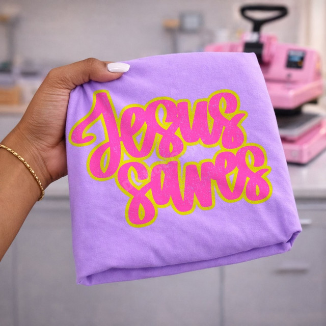 Jesus Saves DTF transfer with retro bubble script lettering in hot pink and yellow-green outline on a lavender shirt