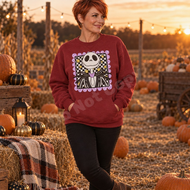 Grinning skeleton head DTF transfer in a pinstripe suit with purple bow, framed by a checkerboard and gold star panel with a scalloped lavender polka-dot border Shown on a Antique Cherry Red crewneck sweatshirt.