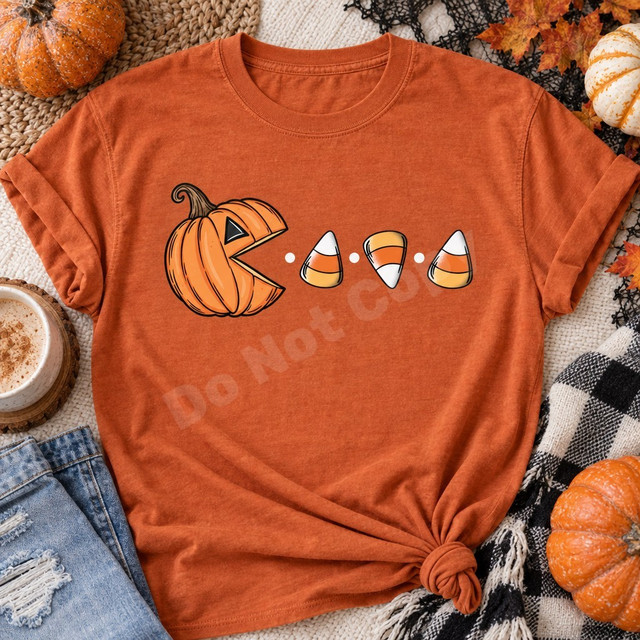 Pac-Man style jack-o-lantern DTF transfer chasing candy corn pieces and dots across an orange Halloween shirt Shown on a Burnt Orange t-shirt.