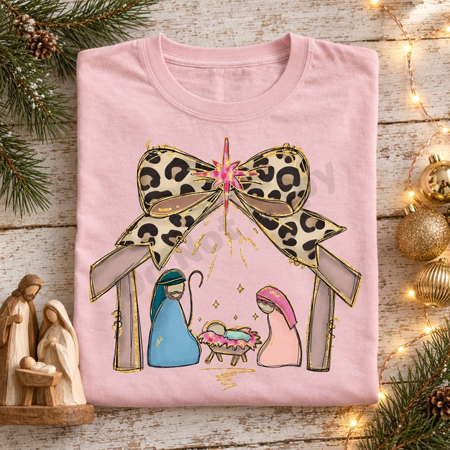 Nativity scene DTF transfer with Mary, Joseph, and baby Jesus beneath a leopard-print bow and glittering pink star Shown on a Blossom t-shirt.