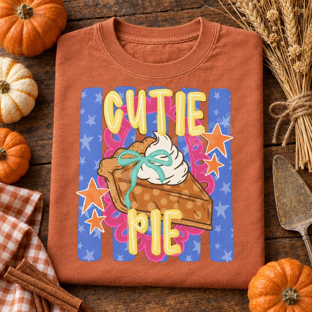 Cutie Pie DTF transfer featuring a hand-drawn pumpkin pie slice with whipped cream and mint bow, pink scalloped doily, orange stars, and blue star-striped background Shown on a Terracotta t-shirt.