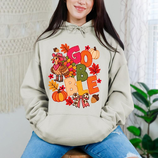 Gobble Western Turkey DTF Transfer | Fall Thanksgiving Design, colorful western-style turkey with pumpkins, autumn leaves, acorns, and bold “GOBBLE” lettering displayed on a cream hoodie