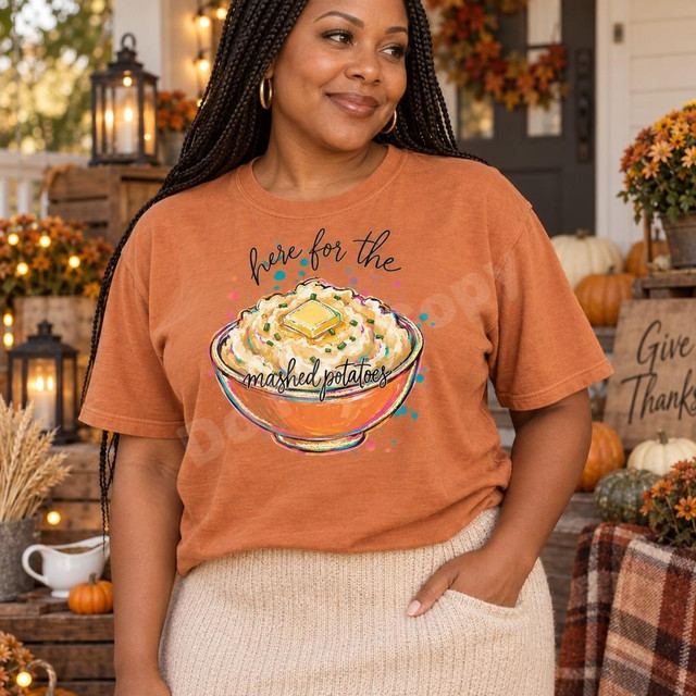 Here For The Mashed Potatoes DTF Transfer | Funny Thanksgiving Food Design, woman wearing an orange shirt featuring a colorful bowl of mashed potatoes and the phrase “Here for the mashed potatoes” in a cozy autumn Thanksgiving setting.