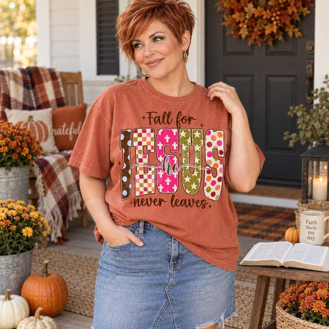 Fall for Jesus He Never Leaves DTF Transfer | Autumn Faith Word Art Design, colorful Christian autumn lettering displayed on a rust-orange T-shirt worn by a woman on a fall-decorated porch