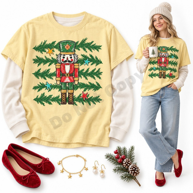 Vintage-style nutcracker soldier DTF transfer in red and green uniform with pine branches and colorful stars on a shirt Shown on a Butter t-shirt.
