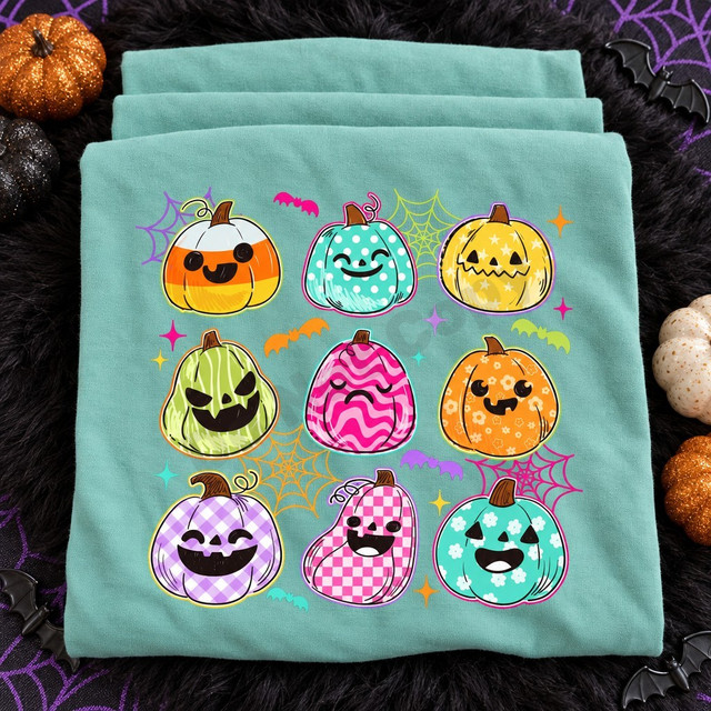 Halloween pumpkin grid DTF transfer with nine patterned jack-o-lanterns, bats, spiderwebs, and sparkles on a teal shirt Shown on a Seafoam t-shirt.