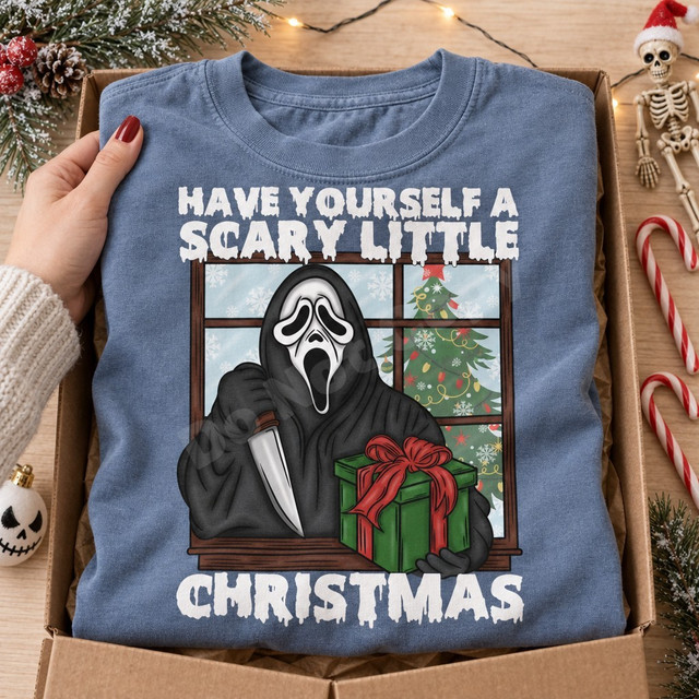 Have Yourself a Scary Little Christmas DTF transfer with Ghostface-style killer holding a knife and wrapped present at a snowy window with Christmas tree Shown on a Chambray t-shirt.