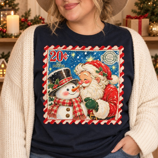 Vintage-style Christmas postage stamp DTF transfer featuring Santa Claus nuzzling noses with a plaid-scarved snowman under a starry night sky, framed by a candy-cane striped stamp border Shown on a Midnight t-shirt.