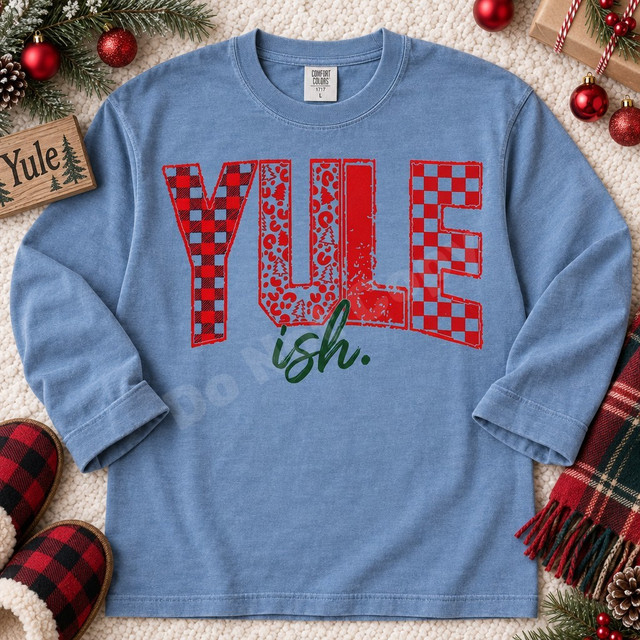 Yule-ish Christmas DTF transfer with mixed buffalo plaid, leopard print, distressed, and checkerboard pattern lettering and dark green brush-script ish. text Shown on a Chambray t-shirt.