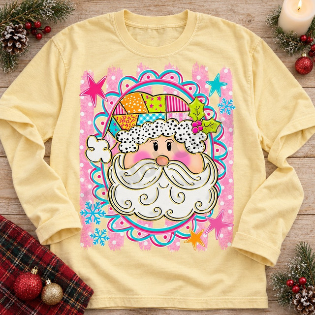 Whimsical Santa face DTF transfer with dotted fur trim, swirly beard, and patchwork hat inside a pink and teal scalloped frame Shown on a Butter t-shirt.