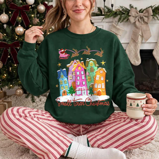 Small Town Christmas DTF transfer with colorful hand-painted houses, snow, and Santa's sleigh and reindeer flying overhead