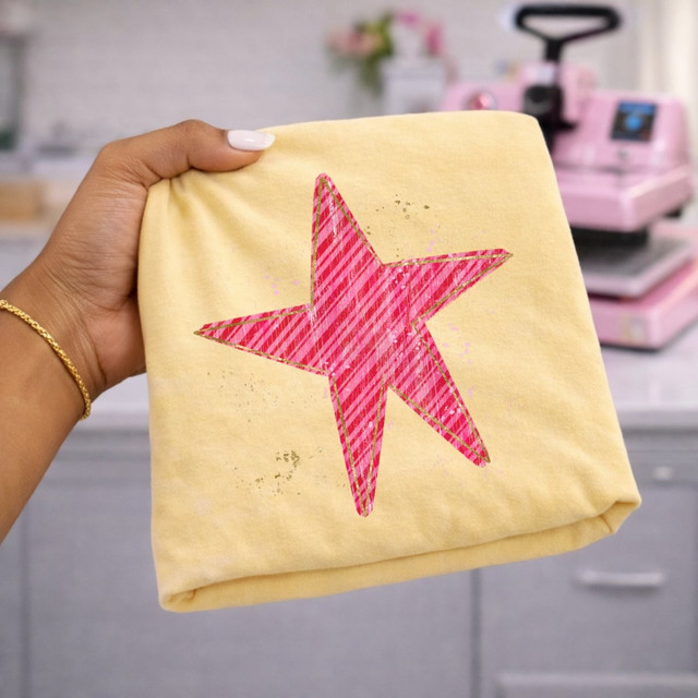 Pink striped star DTF transfer with gold outline and paint-splatter accents on a yellow shirt