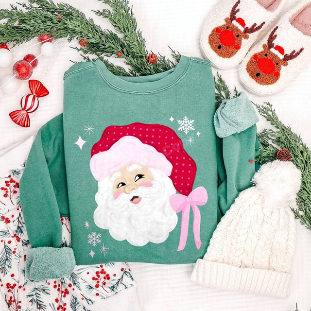 Pink polka-dot Santa face DTF transfer with pink bow and snowflakes on a green sweatshirt