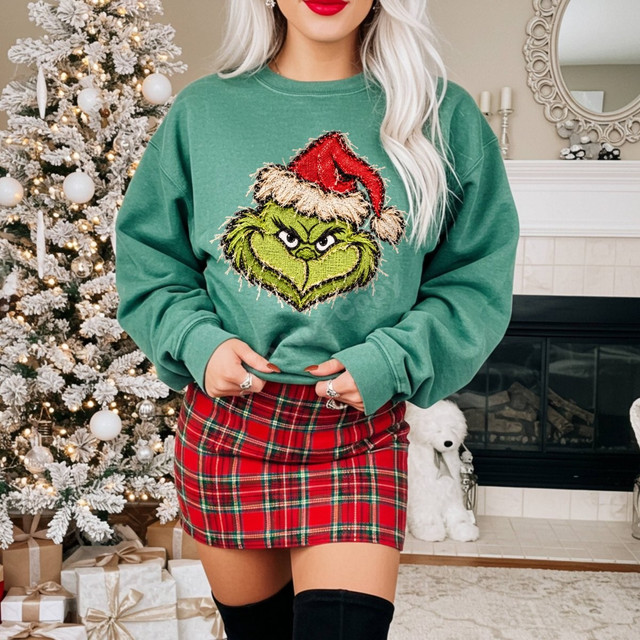 Green grumpy Christmas character face DTF transfer with Santa hat, shown in a faux-embroidered stitched patch style on a sweatshirt