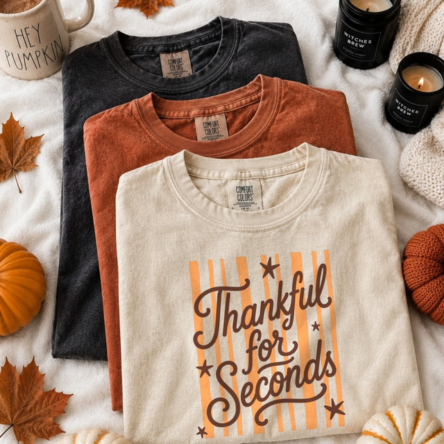Thankful for Seconds DTF transfer with retro script lettering, stars, and orange striped background on a tan t-shirt