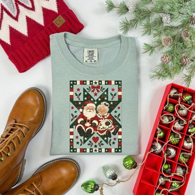 Santa and Mrs. Claus DTF transfer in a vintage quilt-style border with stars and holly on a sage green shirt