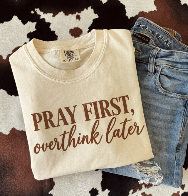 Pray First, Overthink Later DTF transfer in brown script and bold lettering on a cream shirt