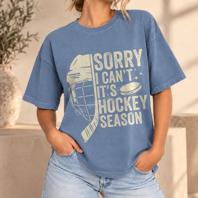 Sorry I Can't It's Hockey Season DTF transfer with distressed goalie mask, hockey stick, and puck graphic in cream ink