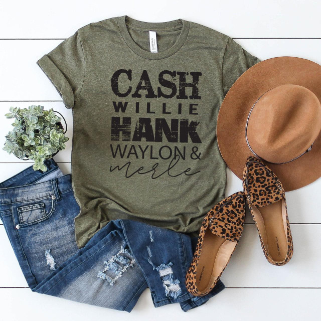 Cash Willie Hank Waylon & Merle BLACK Screen Print Heat Transfer T-shirt, casual outfit with distressed jeans, leopard print flats, a tan cowboy hat, and a small plant on white background.