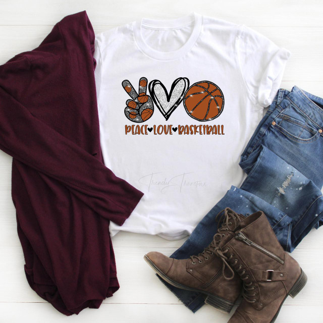 Peace Love Basketball Heart Glitter Sublimation Transfer, a design featuring a peace hand sign, a heart, and a basketball with glitter accents, on a white T-shirt surrounded by jeans, boots, and a maroon scarf.