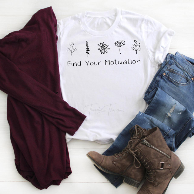 Find Your Motivation Sublimation Transfer, white T-shirt with motivational text and floral design, laid out with jeans, a burgundy scarf, and brown ankle boots on a white wooden background.