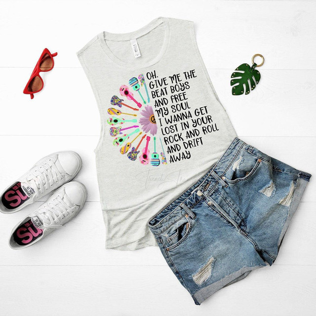 Give Me The Beat Boys Sublimation Transfer, colorful guitar-themed design with lyrics on a sleeveless t-shirt, denim shorts, red sunglasses, and a green monstera leaf keychain on a white background.