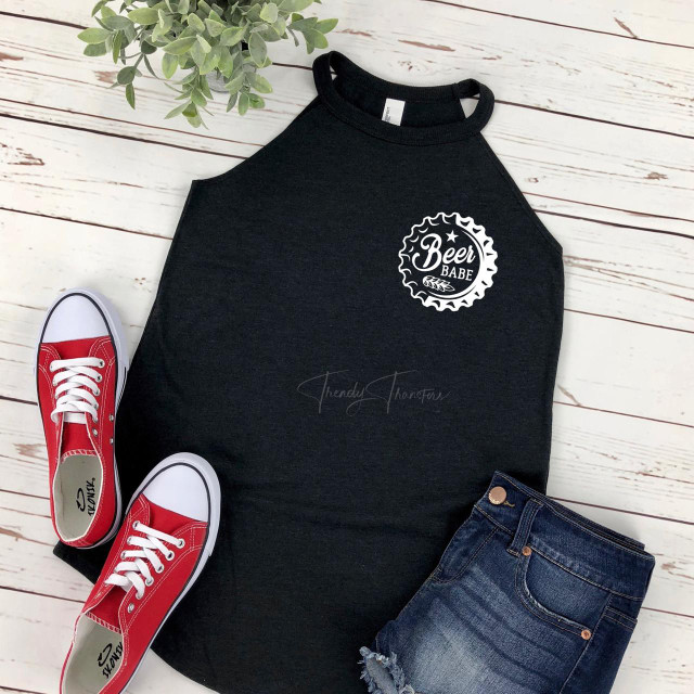 Beer Babe HAT/POCKET/CAN HUGGER Screen Print Heat Transfer, black sleeveless shirt with white beer bottle cap design and text, paired with red sneakers and denim shorts on a white wooden background.