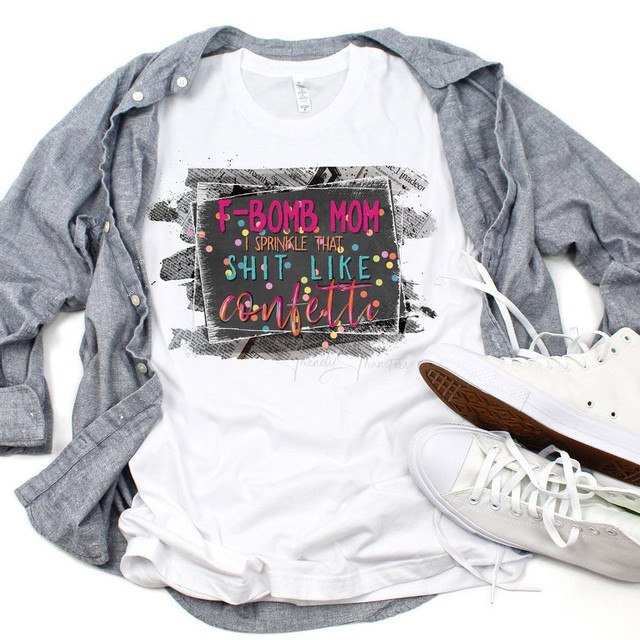 F-Bomb Mom Dark Sublimation Transfer, a humorous and colorful design on a white t-shirt, with a gray shirt and white sneakers placed around it.