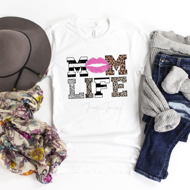 Mom life patterned word art sublimation transfer, white T-shirt with bold leopard, zebra, and striped print letters spelling MOME LIFE with pink lips graphic in the center.